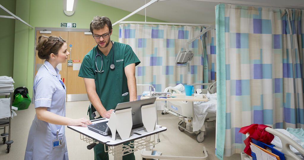 Nurse and Doctor looking at laptop information on the ward