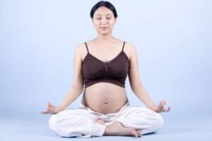Pregnant lady sitting on floor with legs crossed in relaxed pose