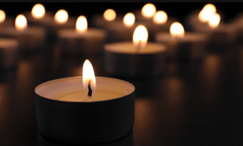 A photo of some tea light candles light on a table in rememberance.