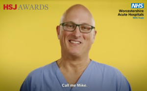 A head and shoulders picture of Dr Mike McCabe wearing theatre scrubs against a yellow background