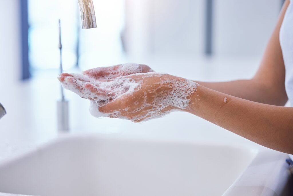 Person washing hands with foamy soap at a sink and tap.