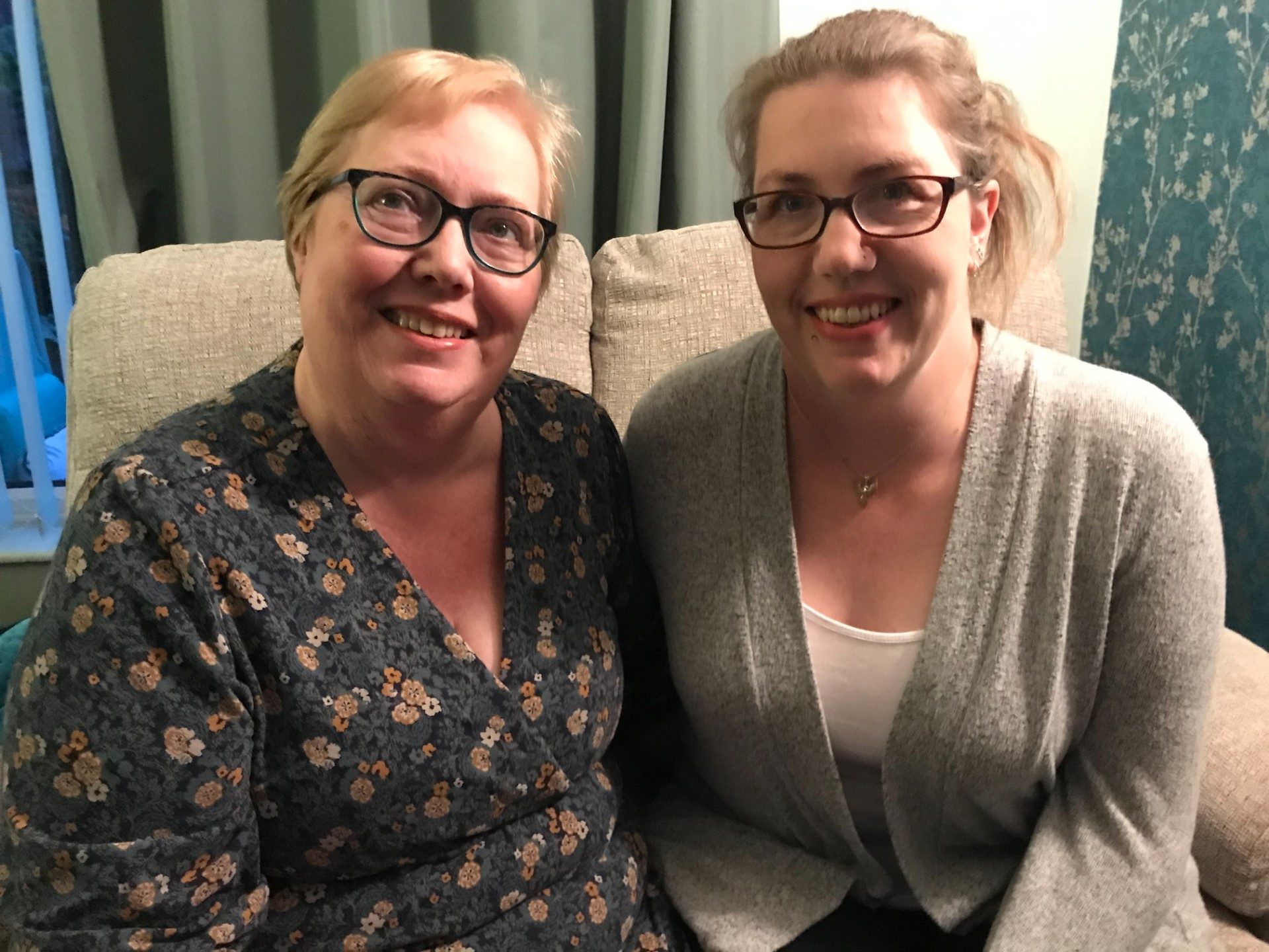 Photograph of Gaynor and Kerry sitting on a chair in room, Portrait smiling shot.