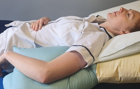 Person lay on back with pillow under affected arm for support