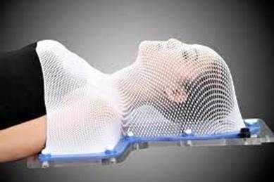 A person lying down with a thermoplastic mesh mask covering the head and neck area
