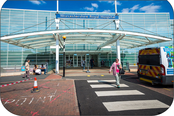 A photo of the main entrance to Worcester Royal Hospital a person is on a zebra crossing walking