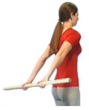 Person has broomstick in hands behind back arms are straight stick is being raised