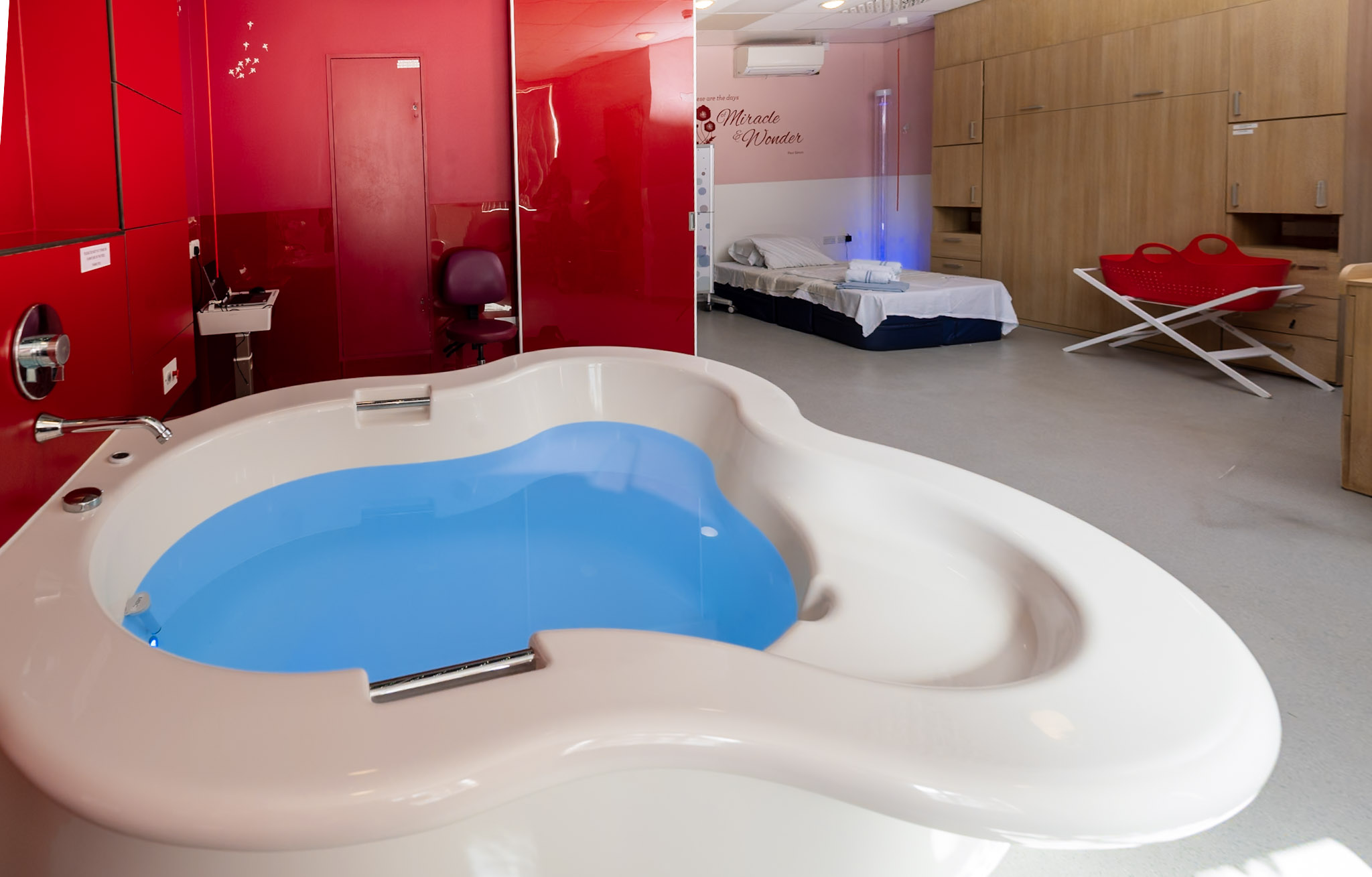 A view of a room in the Meadow Birth Centre, including a birthing pool, a bed and a cot.