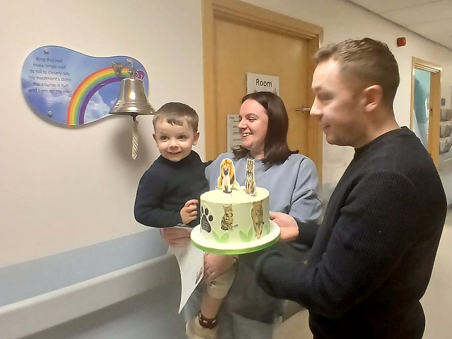Reese with his parents and a celebratory cake marking the end of his treatment.