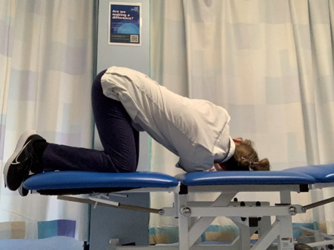 A person on hands and knees on the bed. Thread one hand through underneath to the opposite side, rotating the spine. Hold the stretch.
