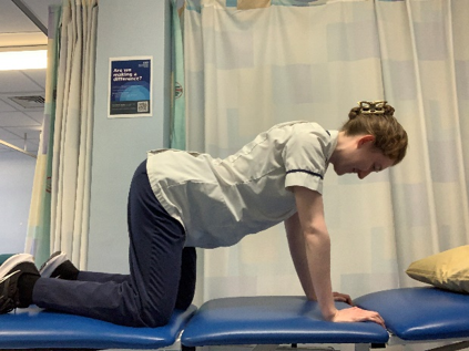 A person on hands and knees on the bed. Slowly arch down the back in a controlled manner.