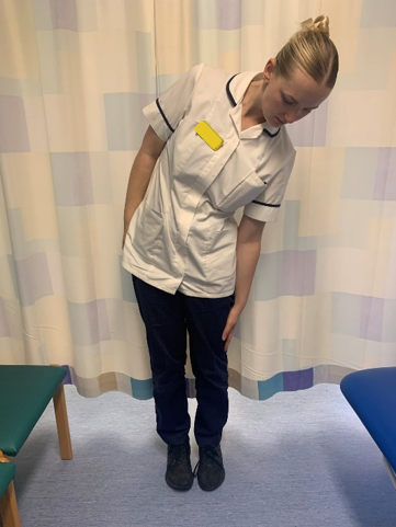 A picture of a person standing upright. Place hands down their sides of the legs. Slowly, slide your left hand down the left leg.