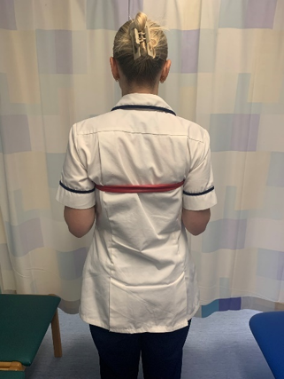 A picture of a person, standing with an exercise band around your upper back, under the shoulder blades. 
