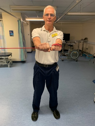 A picture of a person, standing holding the exercise band. Pull the band across to the centre of your body. 