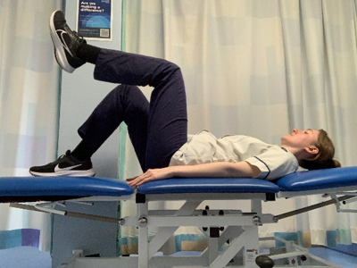 A picture of a person lying on their back on a bed with their knees bent. Slowly lift one leg keeping the knee bent