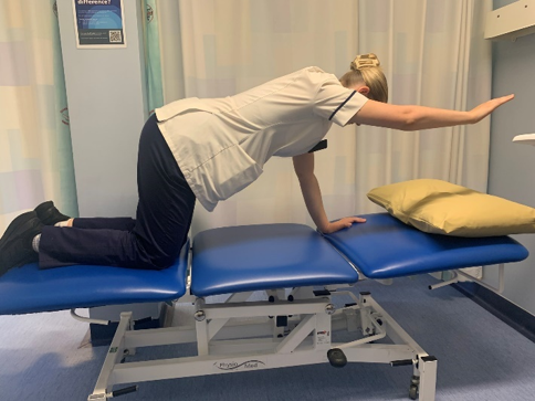 A person on hands and knees on the bed. Slowly lift one arm towards the front horizontally