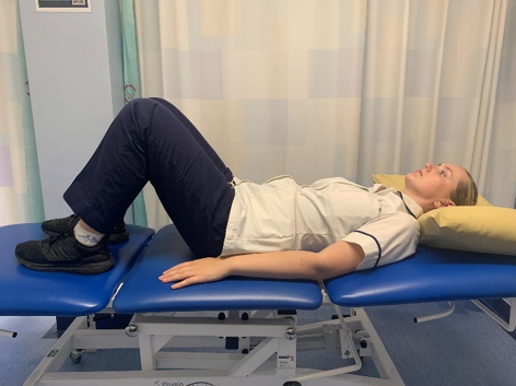 A picture of a person lying on their back on a bed with their knees bent