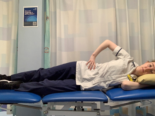 A picture of a person lying on their side. Placed the upper hand on the hip. 