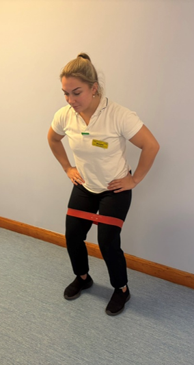 A picture of a person with a looped exercise band round the legs above the knees.