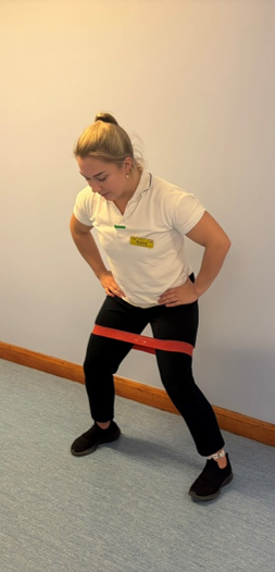 A picture of a person bending slightly at the hips and knees, with a small forwards lean at the trunk. Take a step out to one side and continue stepping in this direction against the band. Complete both directions.