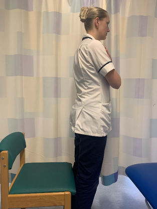 A picture of person standing upright by the chair.